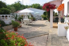 De tuin met een terras voorzien van tafel, stoelen en een parasol.