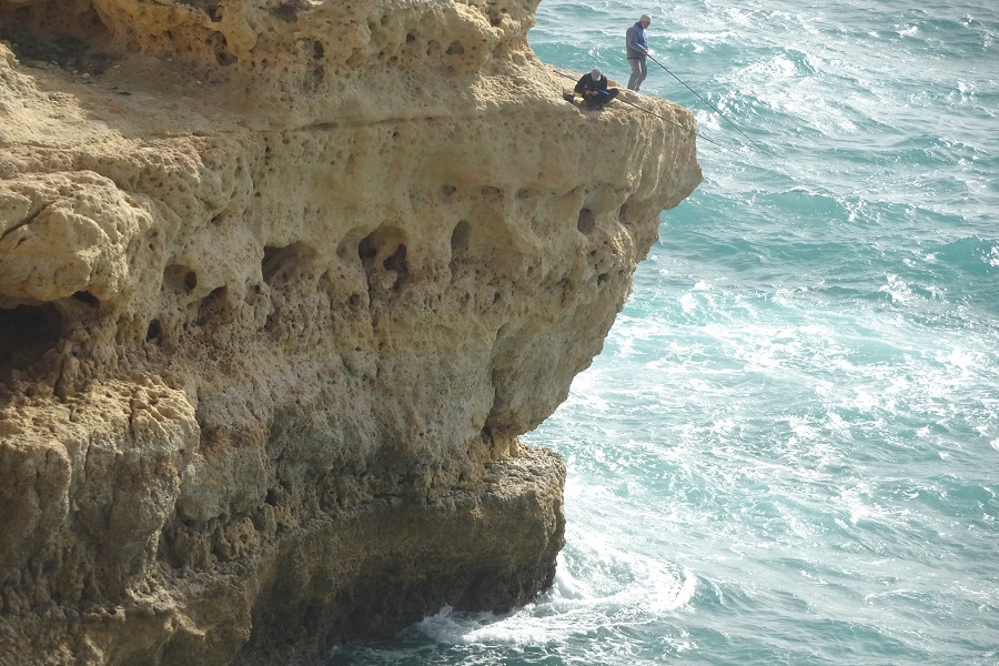 Gevaarlijk vissen op een van de rotspunten langs de kust van de Algarve, Portugal